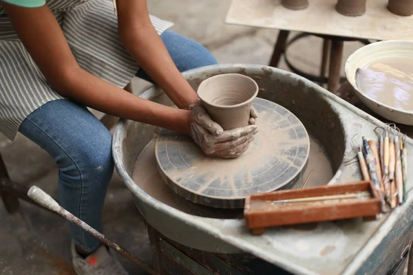 stock image Close-up of concentrated craftswoman in apron sitting at pottery wheel 