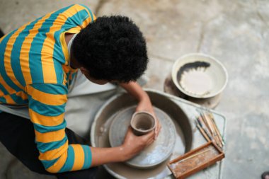 Young Afro teenager hand potter making clay vase in pottery workshop clipart