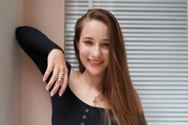 Genç, güzel ve çekici bir kadın. Uzun kahverengi saçlı. Kafede siyah elbiseli..