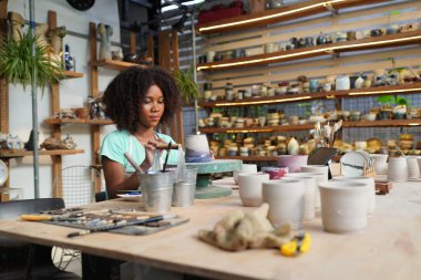 Çömlek atölyesindeki genç Afro kız, işyeri sahibi.