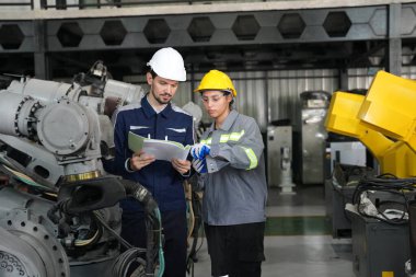 Mühendis fabrikadaki kaynakçıya robotik kaynak işlemini açıklıyor..