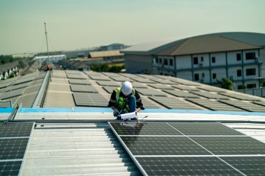 Teknoloji güneş pili, mühendis fabrikanın çatısındaki güneş pilini kontrol ediyor. teknisyen güneş panellerinin bakımını kontrol ediyor