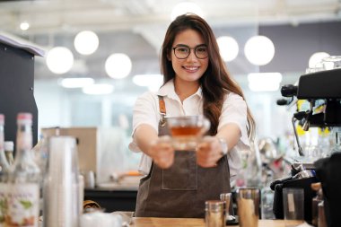 Dükkanında duran mutlu kadın portresi. Neşeli garson kahve dükkanında müşterileri bekliyor. Gri önlüklü başarılı bir küçük işletme sahibi.