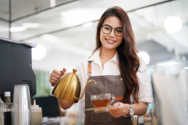 Dükkanında duran mutlu kadın portresi. Neşeli garson kahve dükkanında müşterileri bekliyor. Gri önlüklü başarılı bir küçük işletme sahibi.