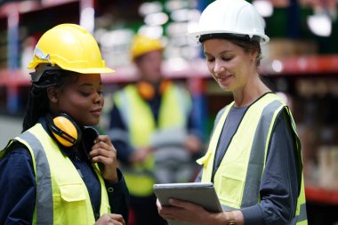 Depo Endüstriyel tedarik zinciri ve lojistik şirketleri içeride. Depo çalışanları envanteri kontrol ediyor. Envanter raflarındaki ürünler.
