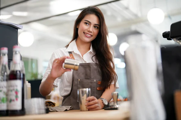 stock image Portrait of happy woman standing in her store. Cheerful waitress waiting for clients at coffee shop. Successful small business owner in casual wearing grey apron