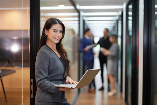 stock image beautiful businesswoman with laptop standing in corridor