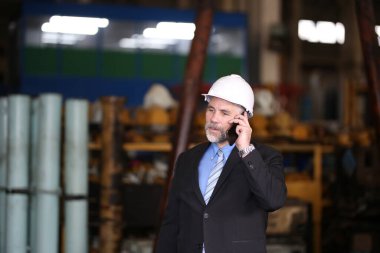 Fabrika deposundaki işadamı cep telefonuyla konuşuyor. Fabrika indurty İş.