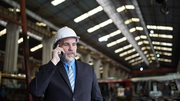 Factory manager or businessman in factory warehouse is talking on mobile phone. Factory industry Business.