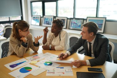 Genç iş adamlarının toplantıda masadaki evrak verilerindeki belgeleri tartışmaları