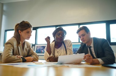 Genç iş adamlarının toplantıda masadaki evrak verilerindeki belgeleri tartışmaları