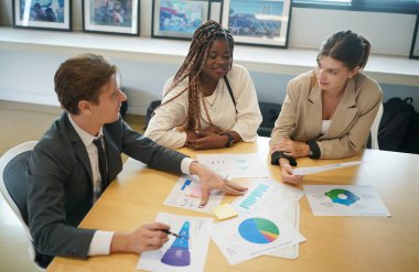 Genç iş adamlarının toplantıda masadaki evrak verilerindeki belgeleri tartışmaları