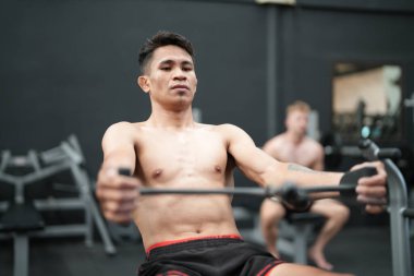 Spor salonunda ya da spor salonunda çapraz eğitim ekipmanları üzerinde egzersiz yapan genç aktif sporcu