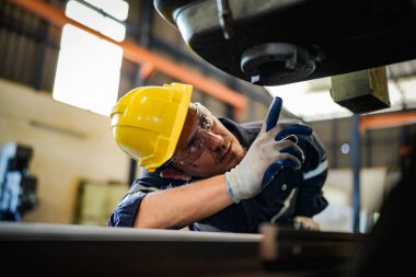 Torna operatörü işine odaklandı. Üniformalı ve kasklı işçiler torna tezgahında çalışıyor, fabrikada. Endüstriyel üretim, metal mühendisliği, imalat.