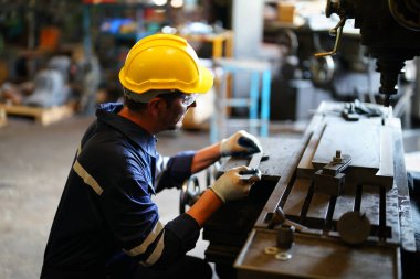 Torna operatörü işine odaklandı. Üniformalı ve kasklı işçiler torna tezgahında çalışıyor, fabrikada. Endüstriyel üretim, metal mühendisliği, imalat.