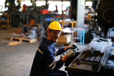 Torna operatörü işine odaklandı. Üniformalı ve kasklı işçiler torna tezgahında çalışıyor, fabrikada. Endüstriyel üretim, metal mühendisliği, imalat.