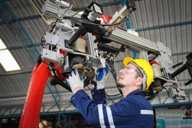 Erkek teknisyen bir robot kolu dijital tabletle programlar ve bir fabrikada robot montajı yapar. Fabrikada çıraklık mühendisliği programlayan robotlar..