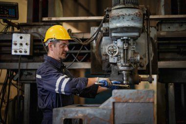 Torna operatörü işine odaklandı. Üniformalı ve kasklı işçiler torna tezgahında çalışıyor, fabrikada. Endüstriyel üretim, metal mühendisliği, imalat.
