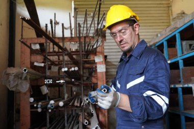 Torna operatörü işine odaklandı. Üniformalı ve kasklı işçiler torna tezgahında çalışıyor, fabrikada. Endüstriyel üretim, metal mühendisliği, imalat.