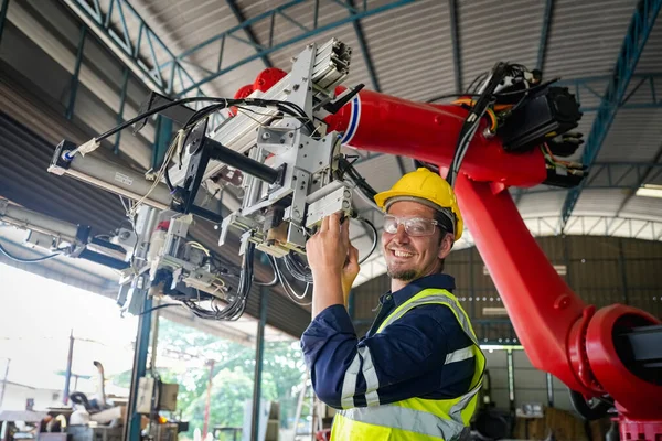 Erkek teknisyen bir robot kolu dijital tabletle programlar ve bir fabrikada robot montajı yapar. Fabrikada çıraklık mühendisliği programlayan robotlar..