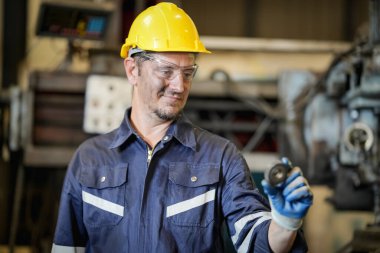 Torna operatörü işine odaklandı. Üniformalı ve kasklı işçiler torna tezgahında çalışıyor, fabrikada. Endüstriyel üretim, metal mühendisliği, imalat.