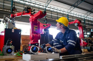 Erkek teknisyen bir robot kolu dijital tabletle programlar ve bir fabrikada robot montajı yapar. Fabrikada çıraklık mühendisliği programlayan robotlar..