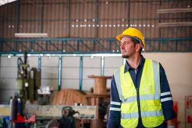 Torna operatörü işine odaklandı. Üniformalı ve kasklı işçiler torna tezgahında çalışıyor, fabrikada. Endüstriyel üretim, metal mühendisliği, imalat.