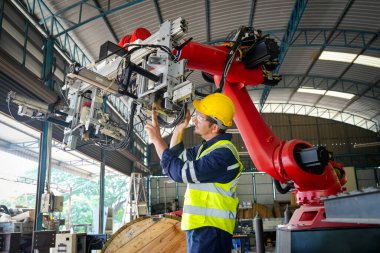 Erkek teknisyen bir robot kolu dijital tabletle programlar ve bir fabrikada robot montajı yapar. Fabrikada çıraklık mühendisliği programlayan robotlar..