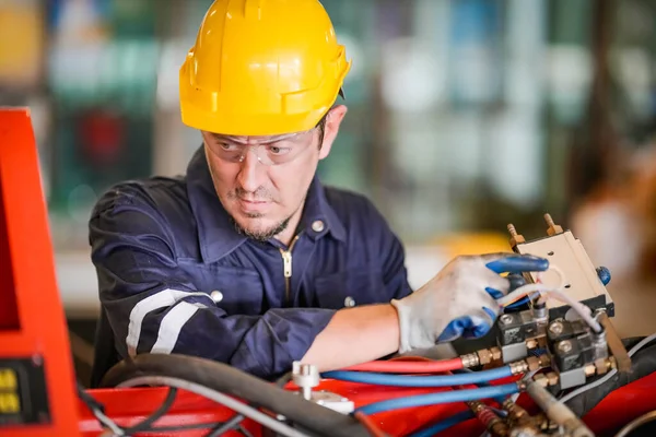 stock image Male technician programs a robot arm with a digital tablet and assembly robot in a factory. Apprentice engineer programming robots in factory.