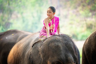 Ormanda fil başında duran genç bir kadının portresi.