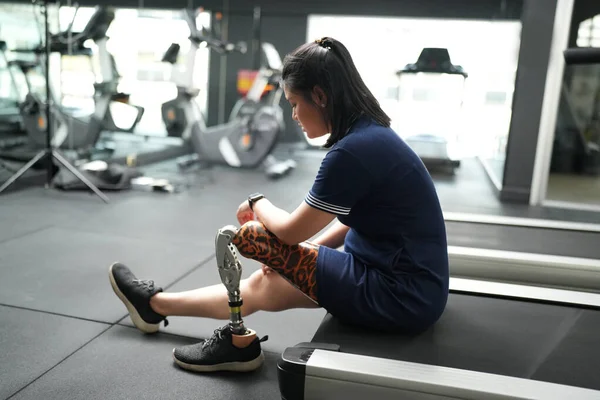 Portrait of disabled athlete woman with prosthetic leg in fitness. Closeup on bionic prosthetic leg.