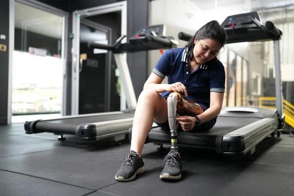 Portrait of disabled athlete woman with prosthetic leg in fitness. Closeup on bionic prosthetic leg.