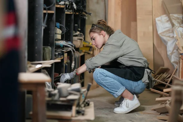 Genç bir kadının küçük işleri. Mobilya atölyesinde ahşabı ölçen genç ve güzel bir kadın işçi..