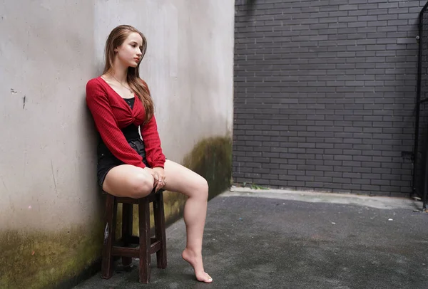 Attractive fashionable young woman posing in sexy clothes against wall.