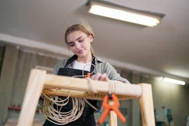 Marangoz DIY atölyesinde çalışan genç ve güzel bir kadın. Küçük işletme sahibi, mobilya fabrikasında çalışan genç bir kadın..