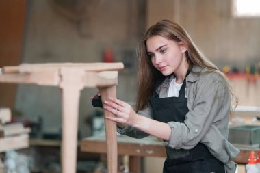 Marangoz DIY atölyesinde çalışan genç ve güzel bir kadın. Küçük işletme sahibi, mobilya fabrikasında çalışan genç bir kadın..