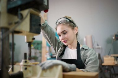 Marangoz DIY atölyesinde çalışan genç ve güzel bir kadın. Küçük işletme sahibi, mobilya fabrikasında çalışan genç bir kadın..