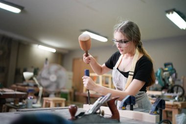 Marangoz DIY atölyesinde çalışan genç ve güzel bir kadın. Küçük işletme sahibi, mobilya fabrikasında çalışan genç bir kadın..