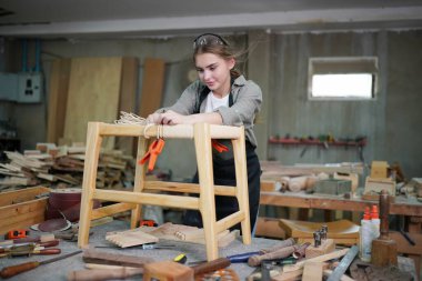 Marangoz DIY atölyesinde çalışan genç ve güzel bir kadın. Küçük işletme sahibi, mobilya fabrikasında çalışan genç bir kadın..