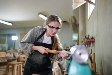 Marangoz DIY atölyesinde çalışan genç ve güzel bir kadın. Küçük işletme sahibi, mobilya fabrikasında çalışan genç bir kadın..
