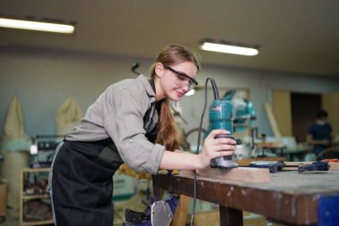 Marangoz DIY atölyesinde çalışan genç ve güzel bir kadın. Küçük işletme sahibi, mobilya fabrikasında çalışan genç bir kadın..
