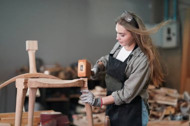 Marangoz DIY atölyesinde çalışan genç ve güzel bir kadın. Küçük işletme sahibi, mobilya fabrikasında çalışan genç bir kadın..