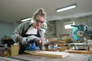 Marangoz DIY atölyesinde çalışan genç ve güzel bir kadın. Küçük işletme sahibi, mobilya fabrikasında çalışan genç bir kadın..