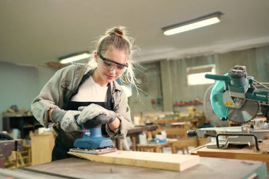 Marangoz DIY atölyesinde çalışan genç ve güzel bir kadın. Küçük işletme sahibi, mobilya fabrikasında çalışan genç bir kadın..