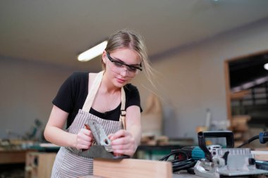 Marangoz DIY atölyesinde çalışan genç ve güzel bir kadın. Küçük işletme sahibi, mobilya fabrikasında çalışan genç bir kadın..