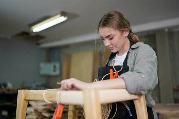 Young beautiful woman doing work in the carpenter DIY workshop room. Small Business owner, young woman who working at furniture factory.