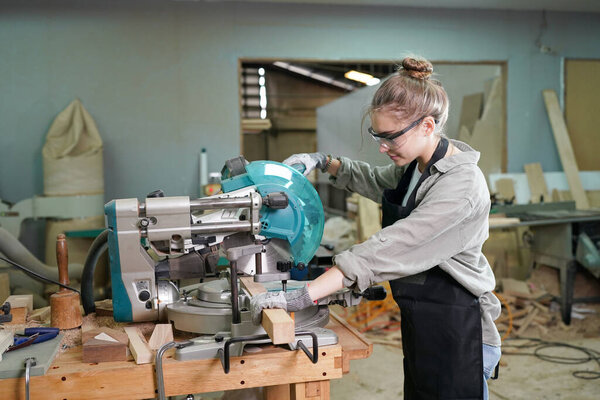Молодая красивая женщина, работающая в мастерской плотника. Владелец малого бизнеса, молодая женщина, работающая на мебельной фабрике.