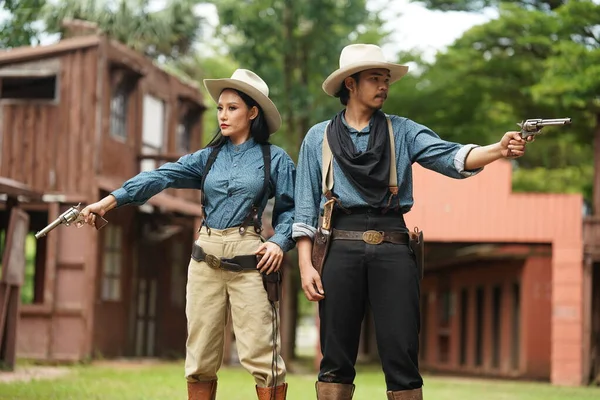 stock image Brutal cowboy and cowgirl  with revolvers on ranch. People with guns, wild west lifestyle