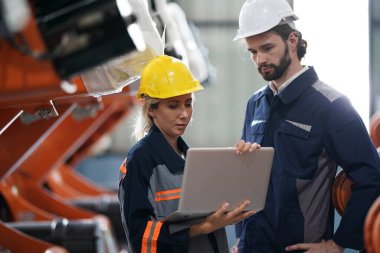 Robot mühendisleri fabrika deposunda robotik kolun bakımı üzerinde çalışıyorlar. İş teknolojisi.