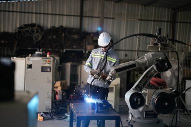 Robot mühendisi fabrika deposunda robotik kolun bakımı üzerinde çalışıyor. İş teknolojisi.